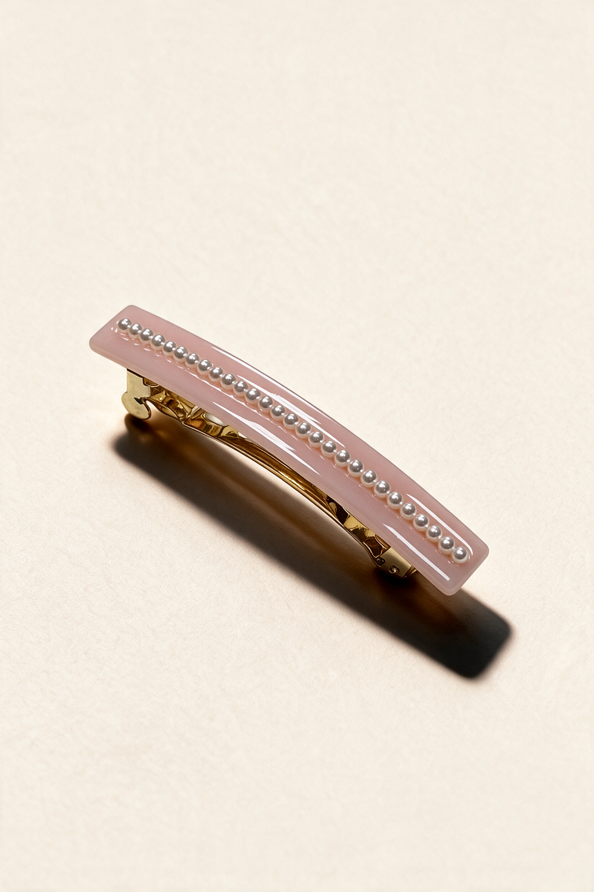 Pearl River Barrette in Pink, with a glossy curved surface and a row of pearl-effect beads.