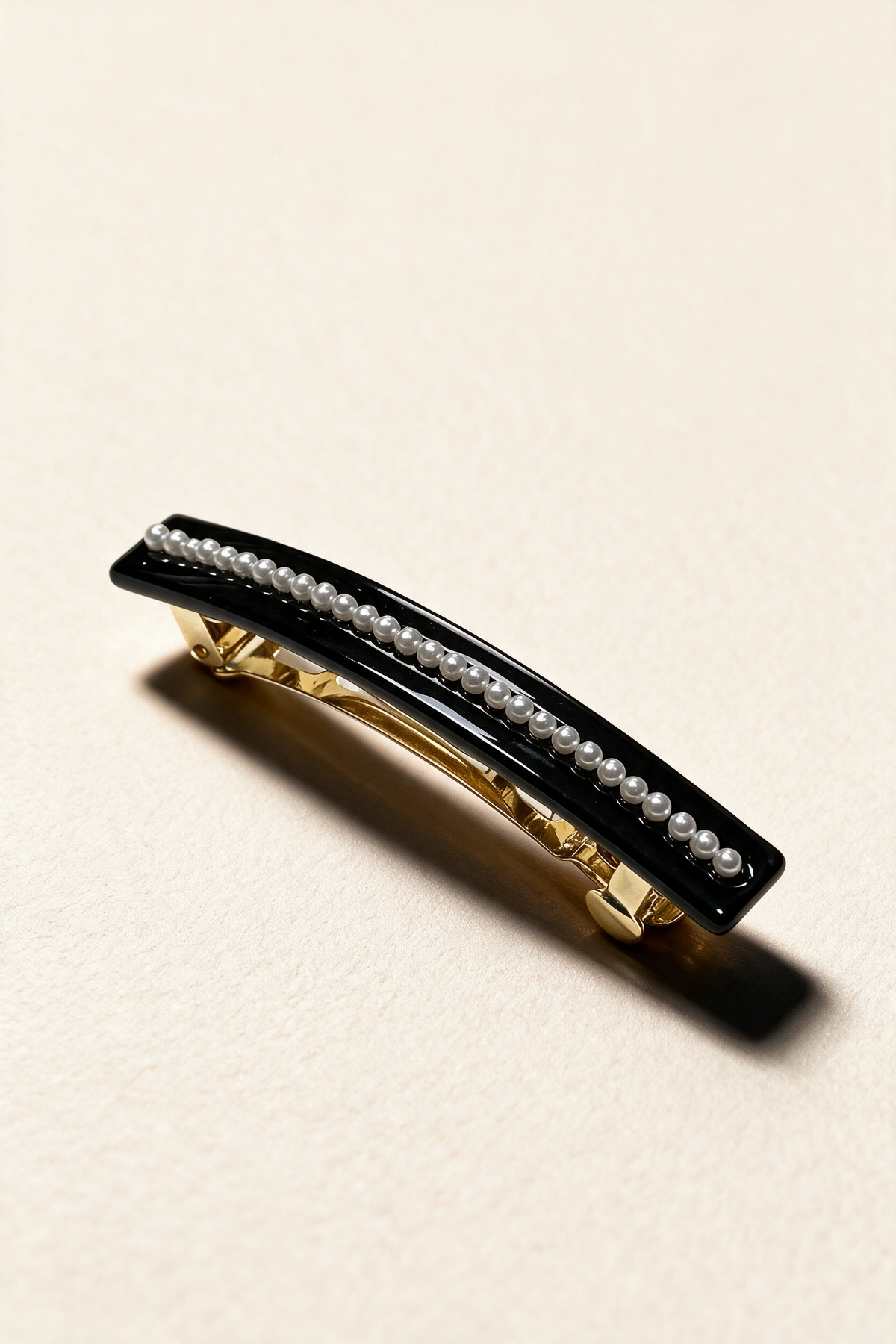 Pearl River Barrette in Black, with a glossy curved surface and a row of pearl-effect beads.